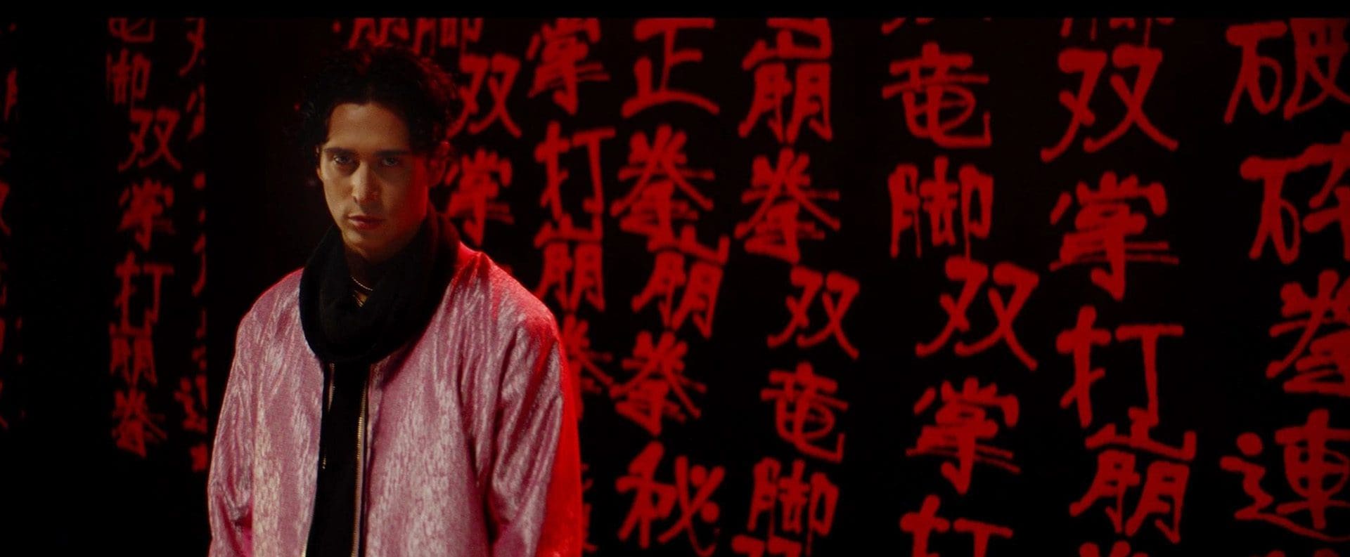 A man standing in front of a wall with chinese writing.